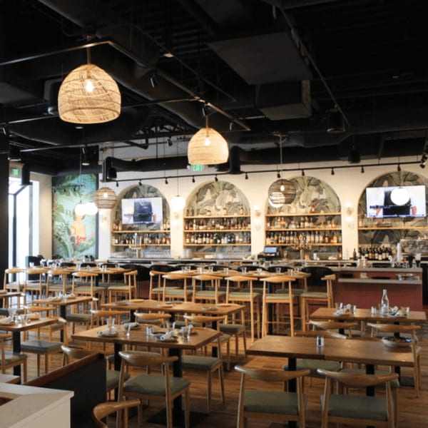 Nardò Italian Restaurant's dining room with wooden tables, chairs, and a bar with arched alcoves.