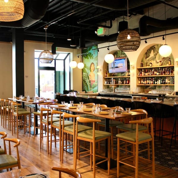 Nardò Italian Restaurant's dining room with high-top tables, chairs, and a bar with bottles and glasses.