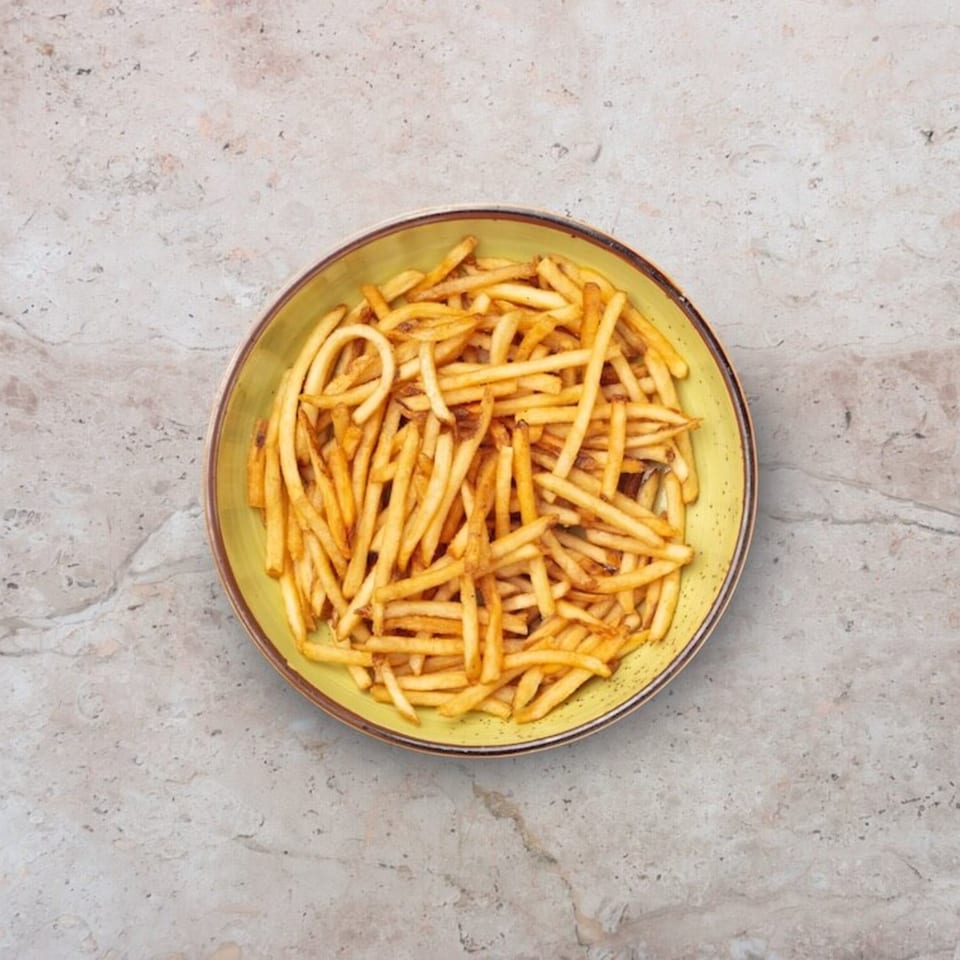 A vibrant yellow bowl filled with crispy, golden french fries, presented on a light gray marble surface.