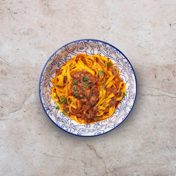Nardò Italian Restaurant's tagliatelle pasta with rich bolognese sauce and fresh parsley in a decorative bowl.