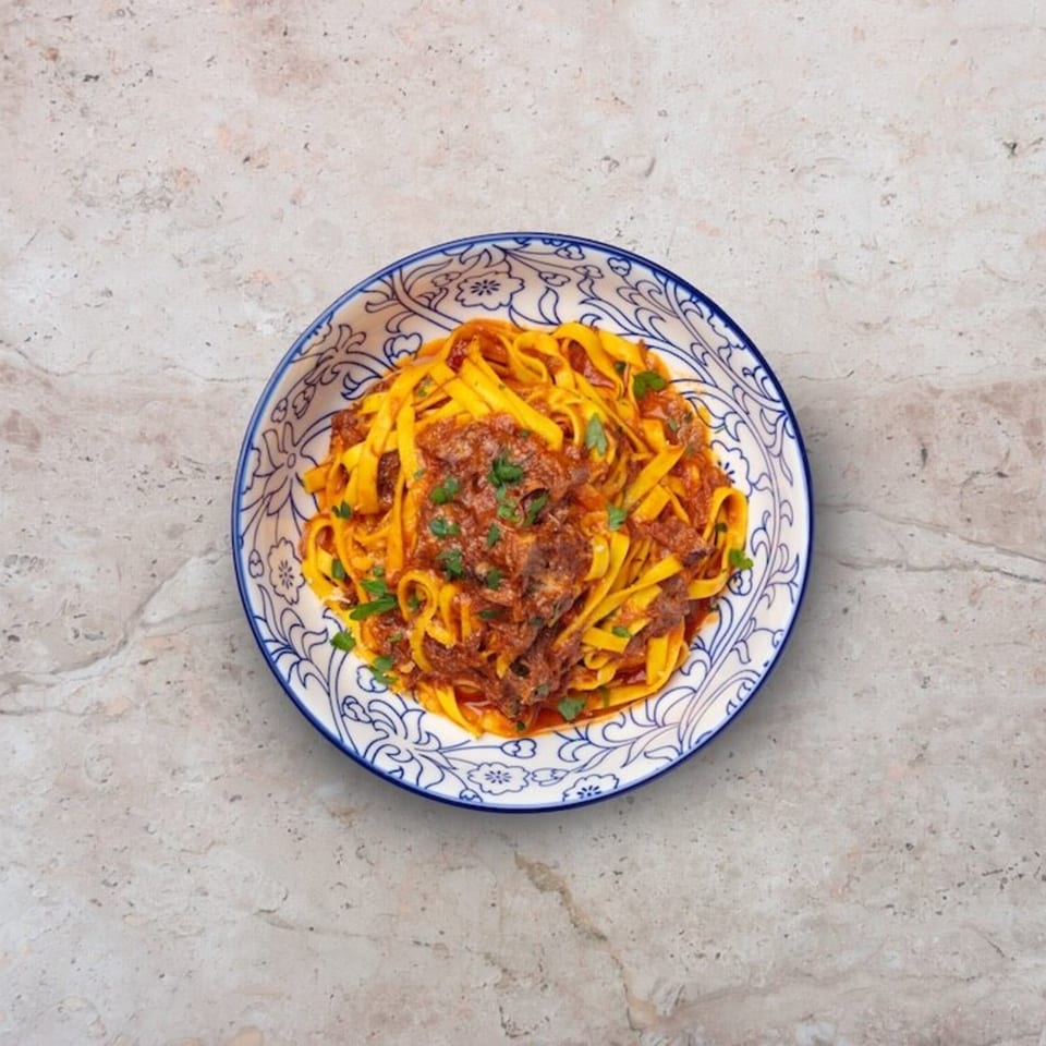 Nardò Italian Restaurant's tagliatelle pasta with rich bolognese sauce and fresh parsley in a decorative bowl.