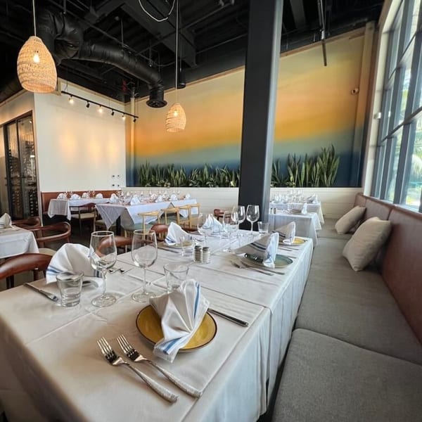 Nardò Italian Restaurant's dining room with set tables, a long banquette, and a colorful mural.
