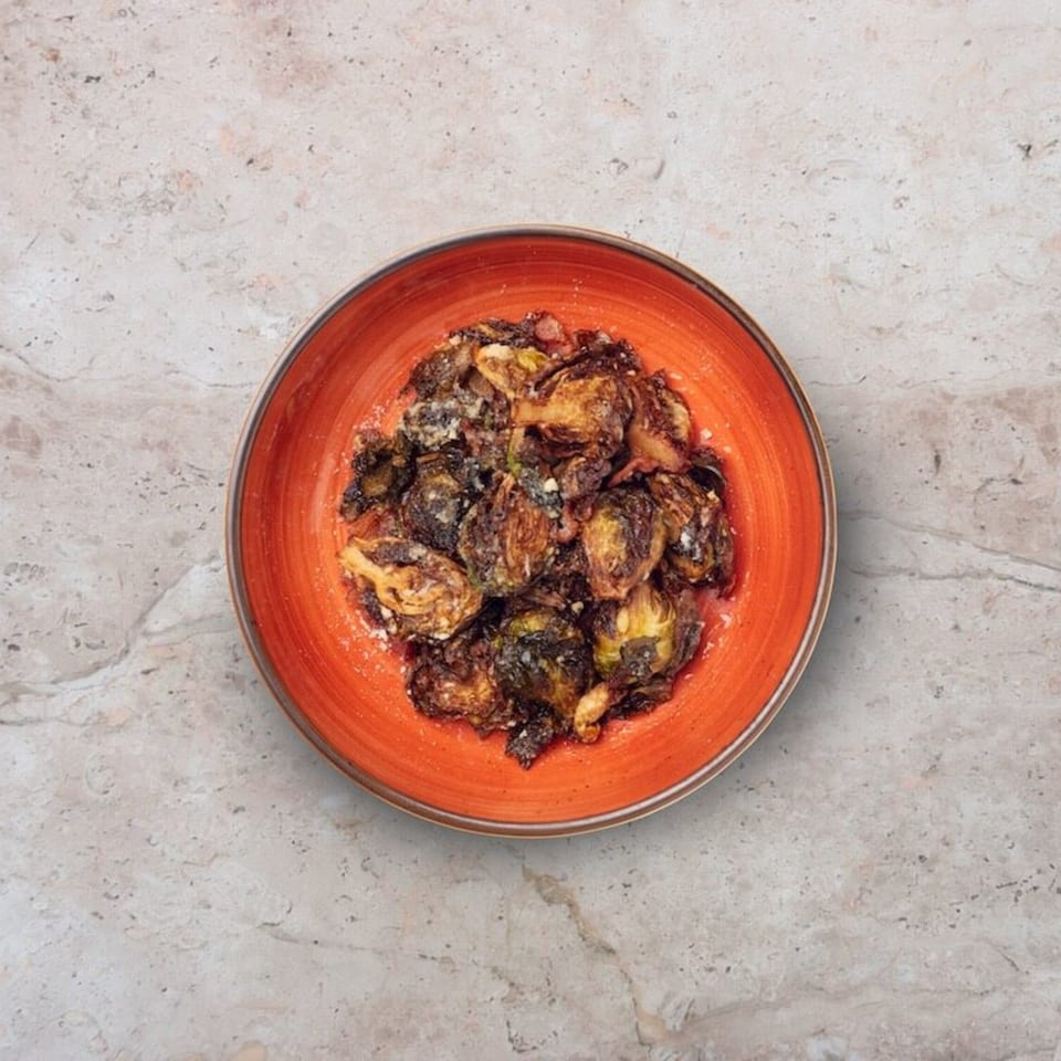 Nardò Italian Restaurant's roasted Brussels sprouts, sprinkled with parmesan cheese, in an orange bowl.