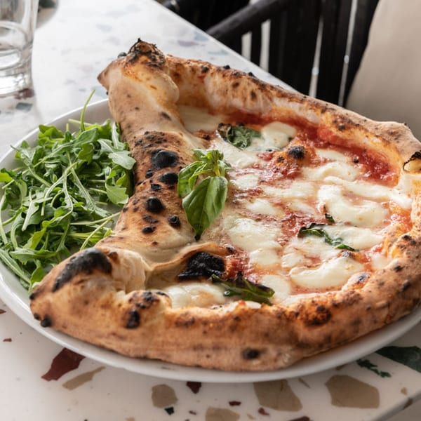 Nardò Italian Restaurant's Neapolitan pizza with fresh mozzarella, basil, and a side of arugula.