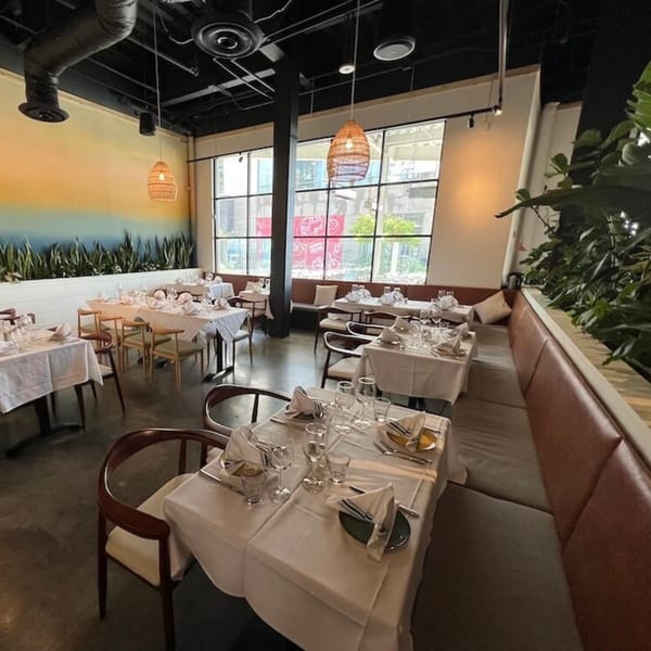 Nardò Italian Restaurant's dining room with set tables, banquettes, and large windows.