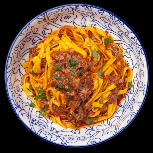 Nardò Italian Restaurant's tagliatelle pasta with rich red meat ragu and fresh parsley in a decorative bowl.