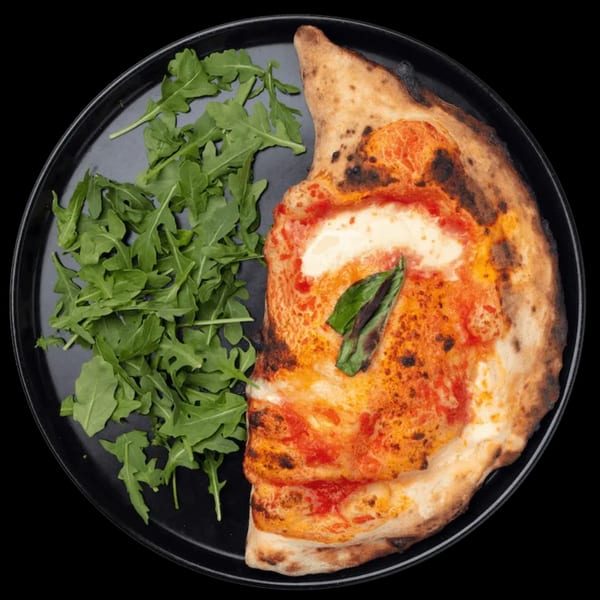 Half a Nardò Italian calzone with tomato sauce, mozzarella, and basil, served with arugula.