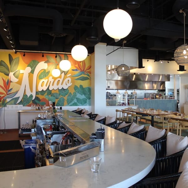 Nardò Italian Restaurant interior with a long bar, mural, dining tables, and open kitchen.