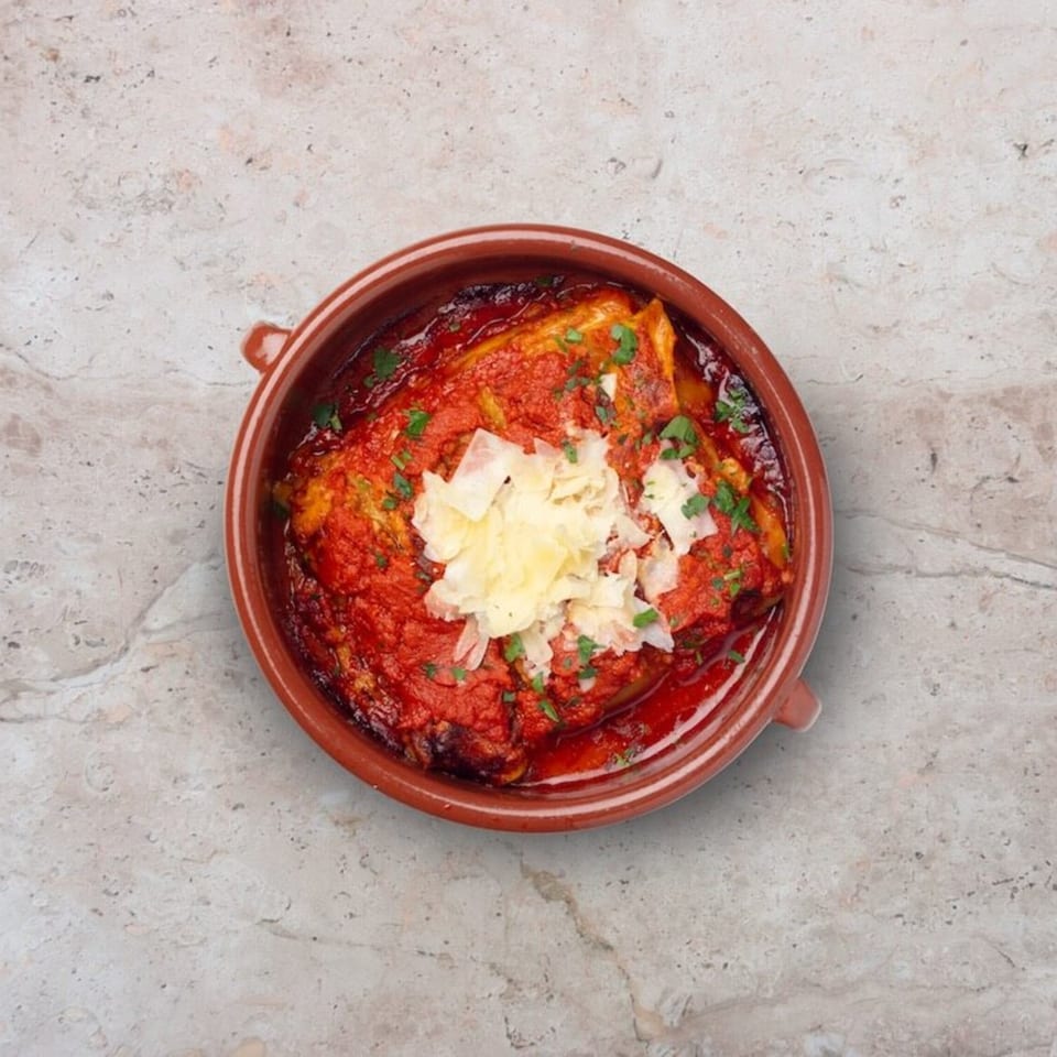 Nardò Italian Restaurant's baked pasta dish with rich red sauce, topped with shaved cheese and parsley.